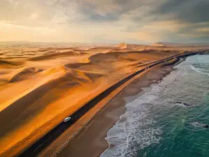 Skeleton Coast sands dunes meet the sea with road and cars
