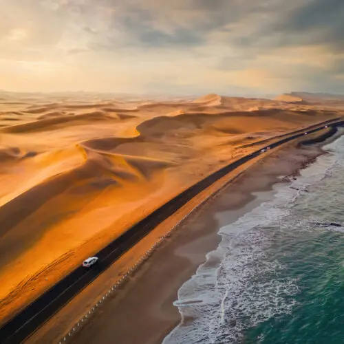 Skeleton Coast sands dunes meet the sea with road and cars