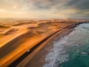 Skeleton Coast sands dunes meet the sea with road and cars