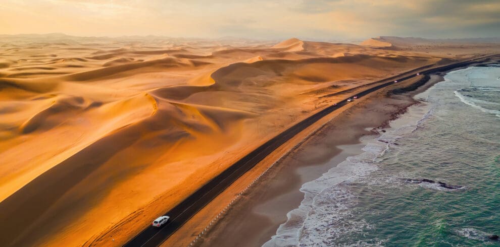 Skeleton Coast sands dunes meet the sea with road and cars